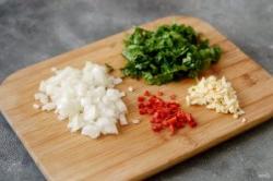 Рецепт - Чашушули с грибами - Шаг 4 -  В этом время подготовьте овощи. Репчатый лук нарежьте на мелкие кубики, острый перец, чеснок и зелень мелко порубите.