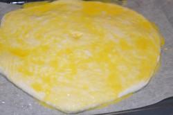 Рецепт - ХАЧАПУРИ ПО-МЕГРЕЛЬСКИ - Шаг 12 -  Застелите противень пергаментной бумагой. Слегка смажьте ее растительным маслом, чтобы изделие не прилипло к дну формы. Осторожно перенесите заготовку на противень. Разбейте яйцо в отдельную небольшую емкость. Немного взболтайте его вилкой. Смажьте силиконовой кисточкой поверхность хачапури. Благодаря яичной смазке, выпечка приобретет красивый золотистый цвет.