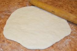 Рецепт - ХАЧАПУРИ ПО-МЕГРЕЛЬСКИ - Шаг 7 -  Рабочую поверхность посыпьте мукой. Выложите на нее тесто. Еще разок обомните его, чтобы выгнать углекислый газ, препятствующий работе дрожжей. По желанию разделите тесто на две части, чтобы испечь два хачапури, но это не обязательно. Я приготовила один большой. Растяните тесто руками (или раскатайте его с помощью скалки) в круглый пласт толщиной около 5 мм.
